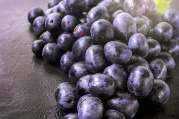 Fresh ripe Bunches of black Grapes berries on kitchen table