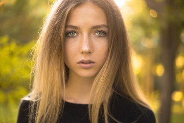 Fototapeta premium Beautiful serious concentrated girl student posing in the park outdoors on grass looking camera.