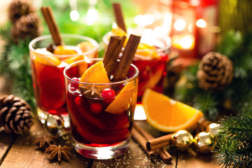 Christmas mulled red wine with spices and oranges on a wooden rustic table. Traditional hot drink at Christmas