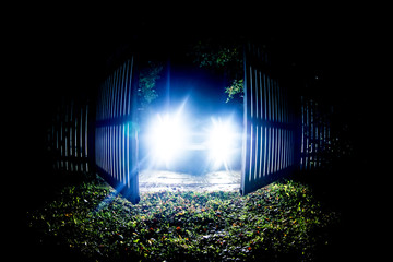 The car stands on the territory of the house at night. Light headlights through the fence