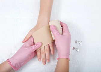 Young female hands wearing pink gloves wrapping elastic ace bandage on young hand and wrist. Medical treatment.