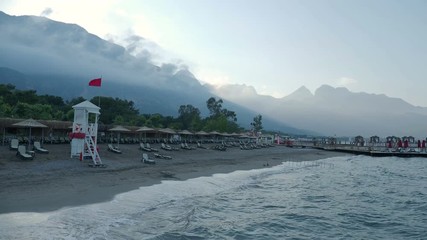 Sunset on the beach. Typical turkish hotel with sun loungers and wooden pontoon. Kemer, Turkey.