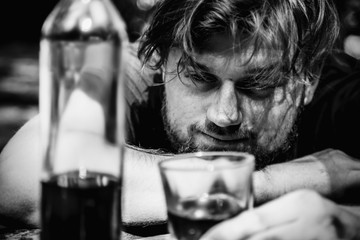 Young male with alcoholic drink looking very sad and depressed. Drunk young people (alcoholism, pain, pity, hopelessness, social problem of dependence concept)