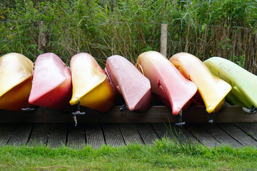 Multicolored inverted canoes on the shore. Multicolored inverted canoe boats