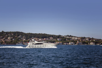 Fototapeta na wymiar Luxury white yacht on Bosphorus in a sunny summer day in Istanbul. European side is in the background.