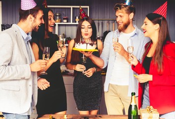 Charming female blowing on candles on birthday cake after making her wish at party.
