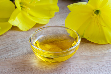 A bowl of evening primrose oil with blooming evening primrose