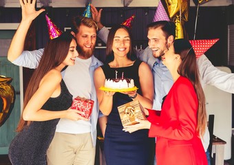 Charming female blowing on candles on birthday cake after making her wish at party.