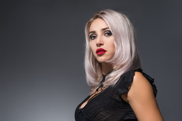 beautiful blonde with red lips on a dark background in a collar with spikes