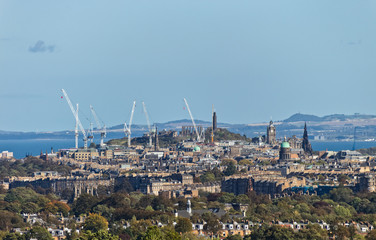 A cityscape photograph of Edinburgh showing Calton Hill, the National Records of Scotland and the Firth of Forth.
