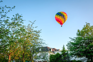 Fototapeta na wymiar Colorful air balloon is riding above a Dutch farm landscape in the summer month of June. This landscape is near the small city of Delden in a region called Twente, in the province of Overijssel