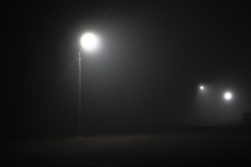 Street lights foggy misty night lamp post lanterns deserted road. Lonely street at night in the...