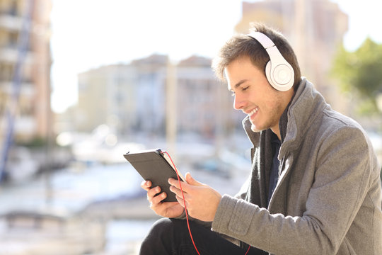 Man learning online using a tablet and headphones in winter
