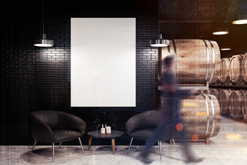 Black brick wine cellar, armchairs and poster, man