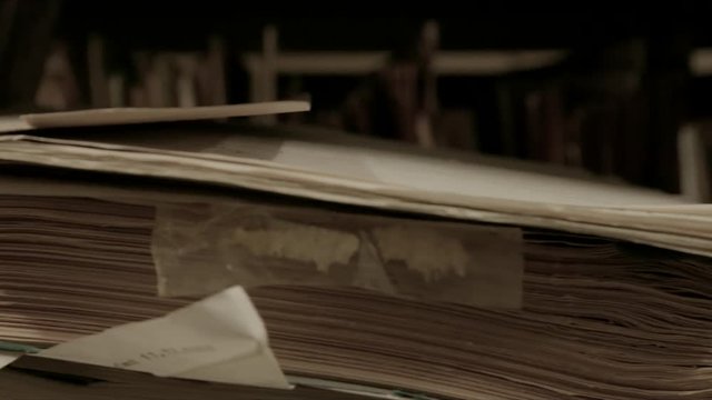 In an archive, slow camera movement via old german folders and archive files.