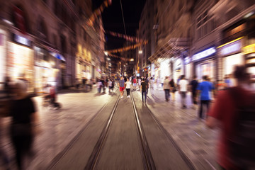 Fototapeta na wymiar Blurry motion image of people walking in Istiklal Avenue (the city’s main pedestrian boulevard) at night in Istanbul. The street which is lined with 19th-century buildings, shopping chains and cafes.