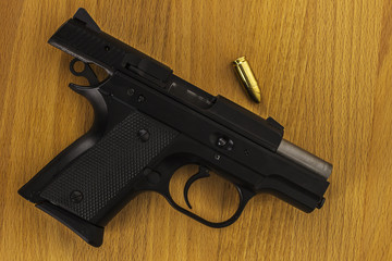Subcompact 9mm pistols, very small gun with bullet on wood desk