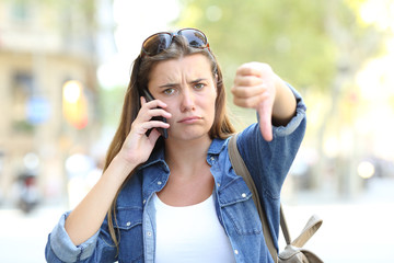 Angry girl talking on phone with thumbs down