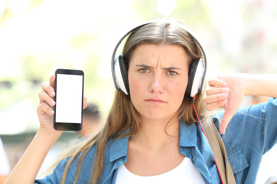 Angry teen listening to music showing phone screen