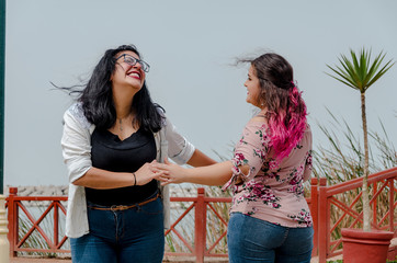 Two chubby girls with inline skates by the park happy taken by hands