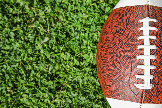 Ball for American football on fresh green field grass, top view. Space for text