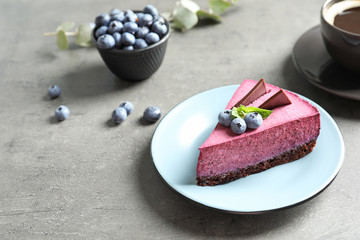 Plate with piece of tasty blueberry cake on gray table