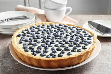 Plate with tasty blueberry cake on gray table