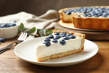 Plate with tasty blueberry cake on wooden table
