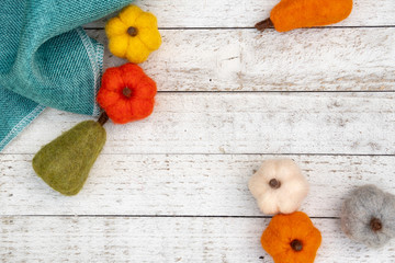 Flat lay autumn background with felt fuzzy pumpkins and gourds over a white wooden background. Fall concept with copy space