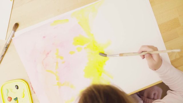 Top view. Rotation. Young artist painting on paper with watercolors using a brush
