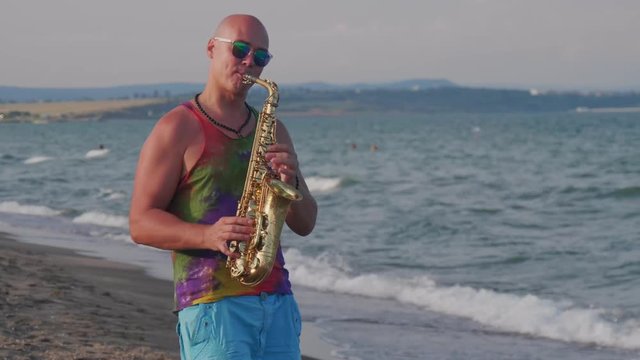 bald saxophonist playing near the sea