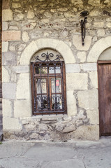The window is framed by a stone arch with wrought-iron bar  on the Sharambeyan street in the Museum Tufenkian Old Dilijan
