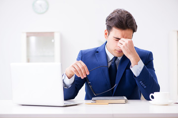 Young handsome employee siitting at office 