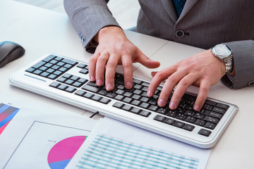 Finance professional working on keyboard with reports
