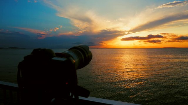 A camera with a TV shoots a beautiful sunset at the sea