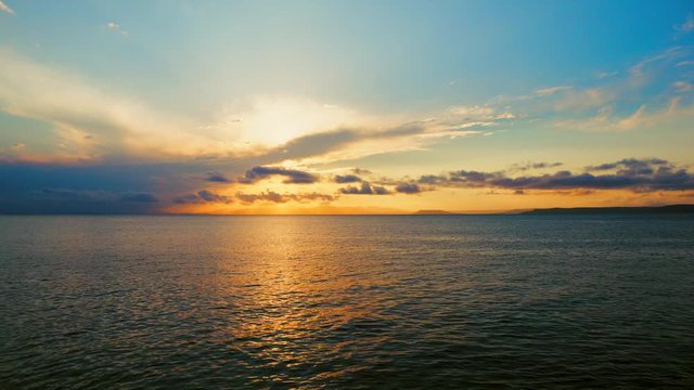 Sea view on a pleasant summer evening: a beautiful sunset, colored clouds, a pure sea with a yacht, the glint of the sun on the water. Sea, ocean, natural video for tourist, resort and meditative site
