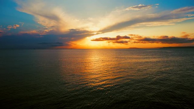 Sea view on a pleasant summer evening: a beautiful sunset, colored clouds, a pure sea with a yacht, the glint of the sun on the water. Sea, ocean, natural video for tourist, resort and meditative site