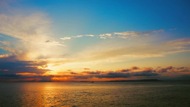 Sea view on a pleasant summer evening: a beautiful sunset, colored clouds, a pure sea with a yacht, the glint of the sun on the water. Sea, ocean, natural video for tourist, resort and meditative site