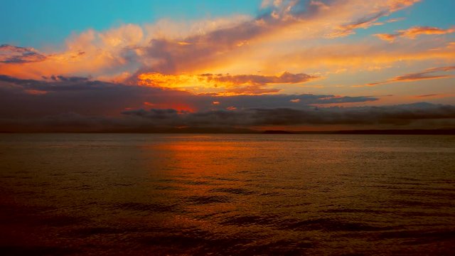 Sea view on a pleasant summer evening: a beautiful sunset, colored clouds, a pure sea with a yacht, the glint of the sun on the water. Sea, ocean, natural video for tourist, resort and meditative site