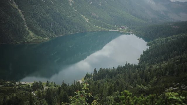 Amazing beautiful blue mountain lake with green forest and high mountains in the background Morskie Oko - Poland europe hill landscape nature peak rock sky tatra close up slow motion