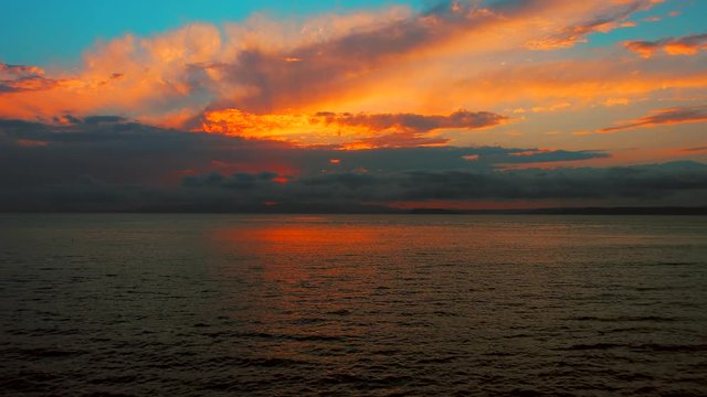 Sea view on a pleasant summer evening: a beautiful sunset, colored clouds, a pure sea with a yacht, the glint of the sun on the water. Sea, ocean, natural video for tourist, resort and meditative site
