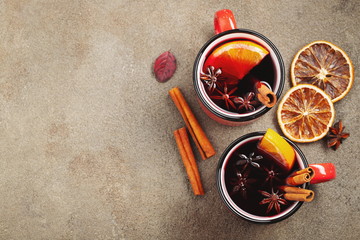 Two cups of christmas mulled wine or gluhwein with spices and orange slices on rustic table top...
