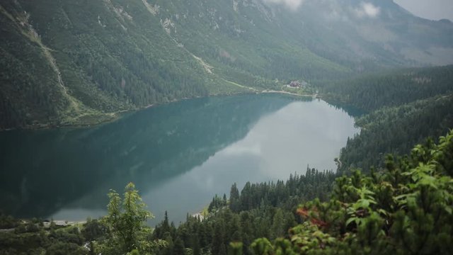 Amazing beautiful blue mountain lake with green forest and high mountains in the background Morskie Oko - Poland europe hill landscape nature peak rock sky tatra close up slow motion