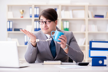Businessman chained with handcuffs to his coffee