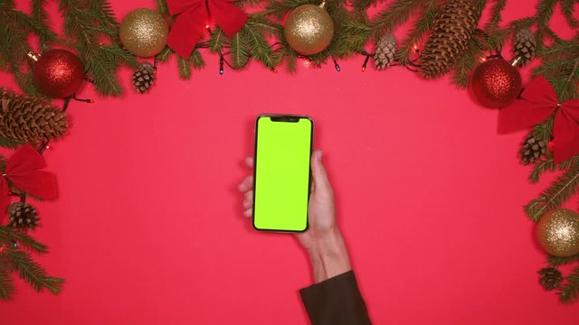 Hand using smartphone against Christmas decorations