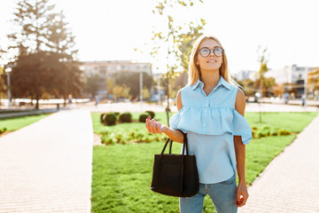 Fototapeta premium Young beautiful girl with glasses, student strolling in the Park, in a good mood