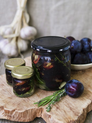 Glass jar with dried plums and fresh rosemary on wooden serving board, selective focus. Close up, copy space