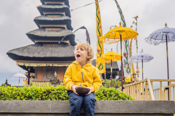 Boy traveler in the background of Pura Ulun Danu Bratan, Bali. Hindu temple surrounded by flowers on Bratan lake, Bali. Major Shivaite water temple in Bali, Indonesia. Traveling with children concept