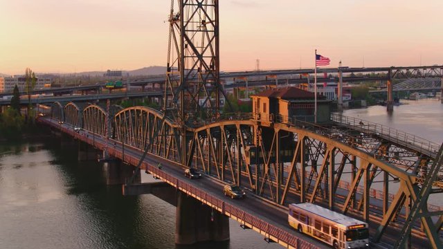 Drone aerial tracking style view of the Hawthorne Bridge with a bus crossing at sunrise in Portland Oregon