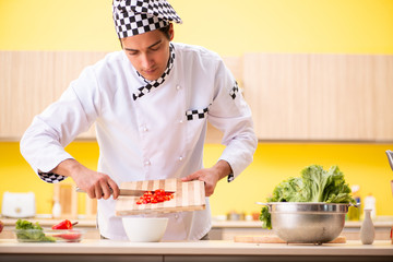 Young professional cook preparing salad at home